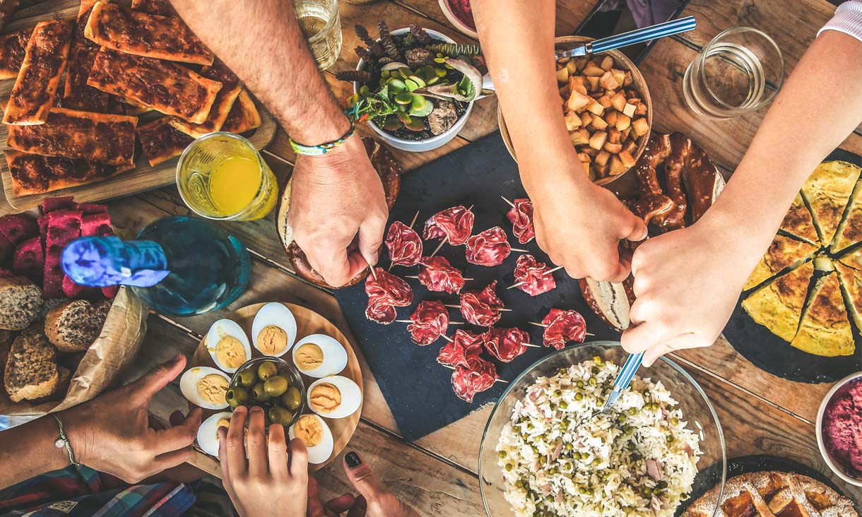 A delicious spread of finger foods at a dinner party, with party guests reach out for different dishes.