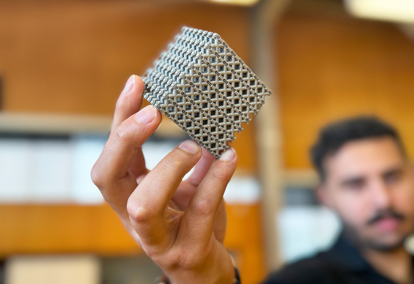 PhD candidate Jordan Noronha holding a sample of the new titanium lattice structure 3D printed in cube form. Credit: RMIT.