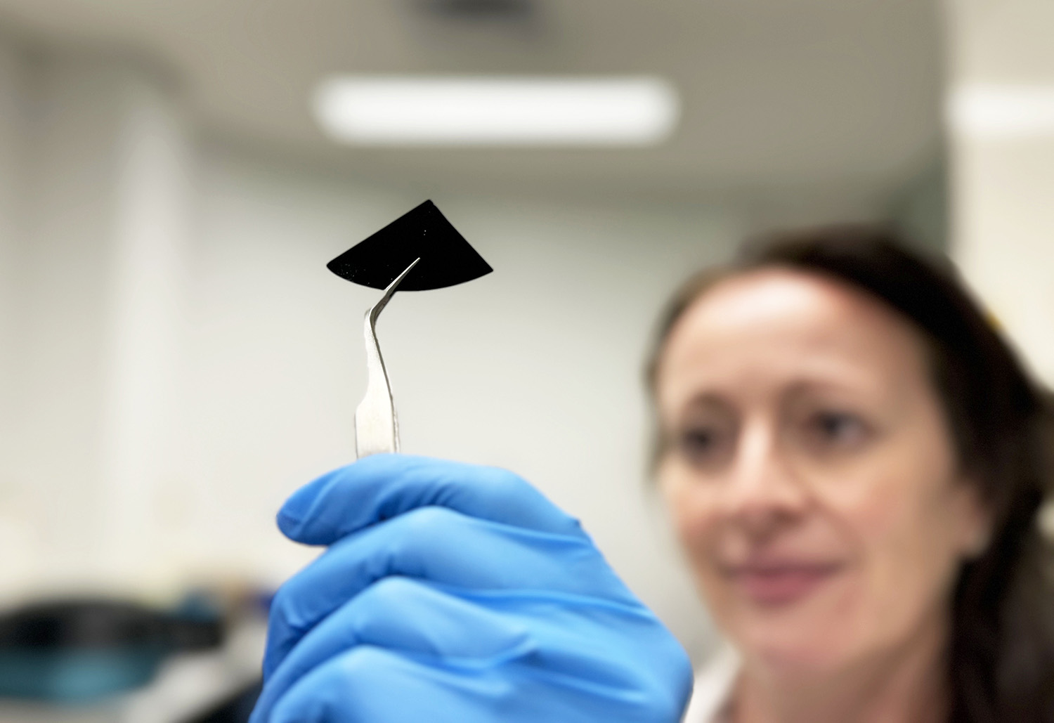 Dr Natalie Borg inspects a sample of the nano spiked silicon sheet. Credit: RMIT.