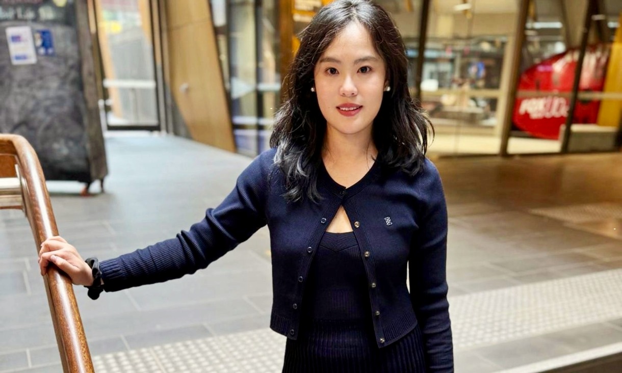 A woman navy blue outfit holding a banister looking at the camera with a smile. 
