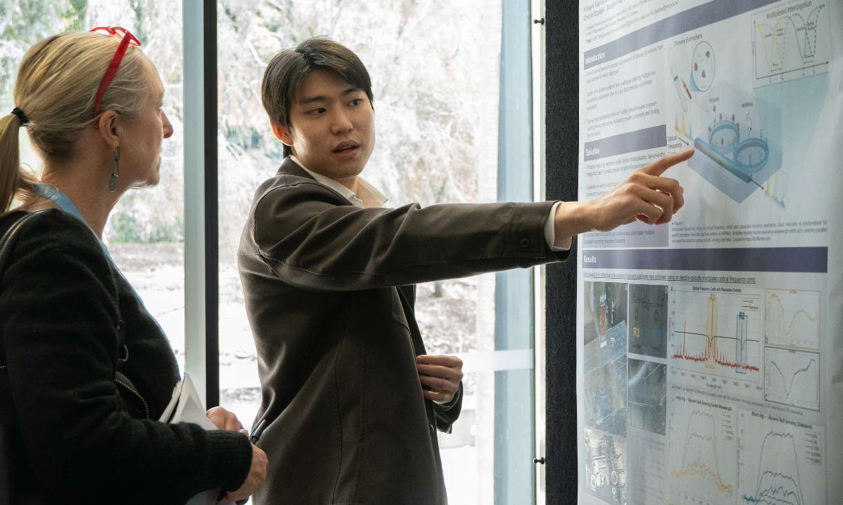 Person pointing and explaining poster to someone else