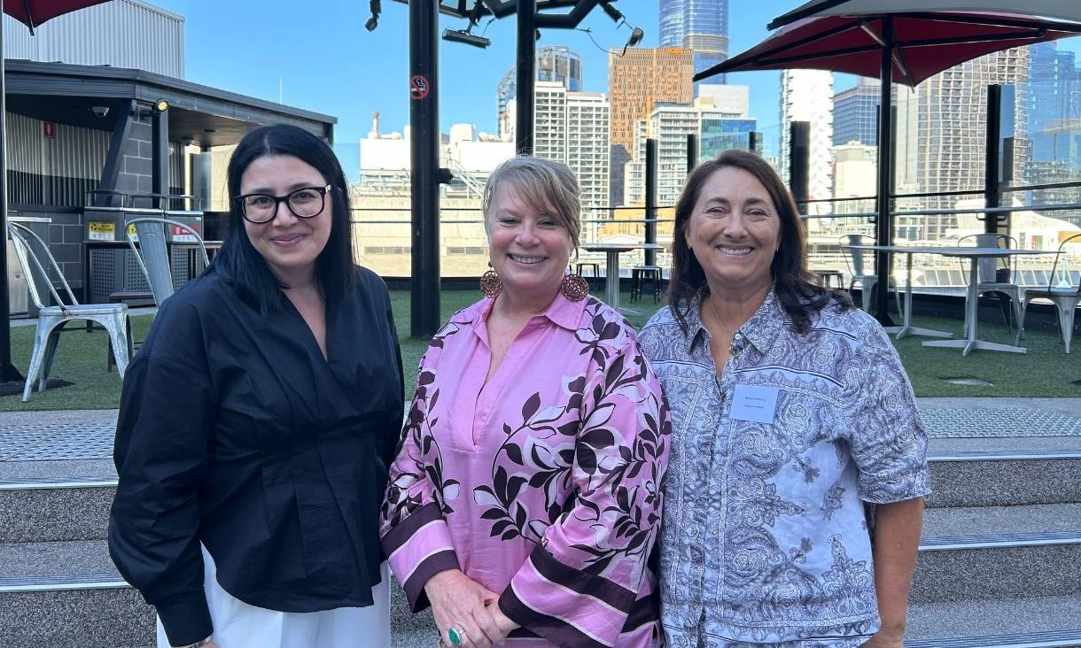 The conference organisers Chrissy, Simone, and Rebecca stand together smiling.