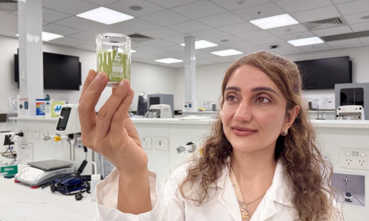 Dr Mahsa Majzoobi holding a beaker of powdered saltbush used in the study.