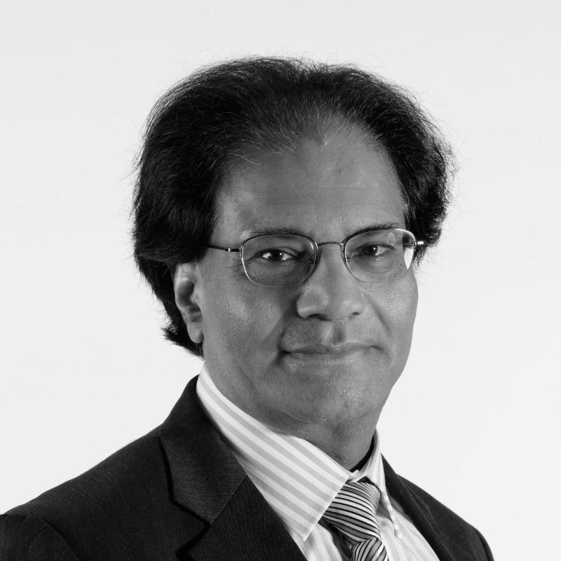 Black and white profile photo of Suresh Bhargava smiling towards the camera against a solid white background.