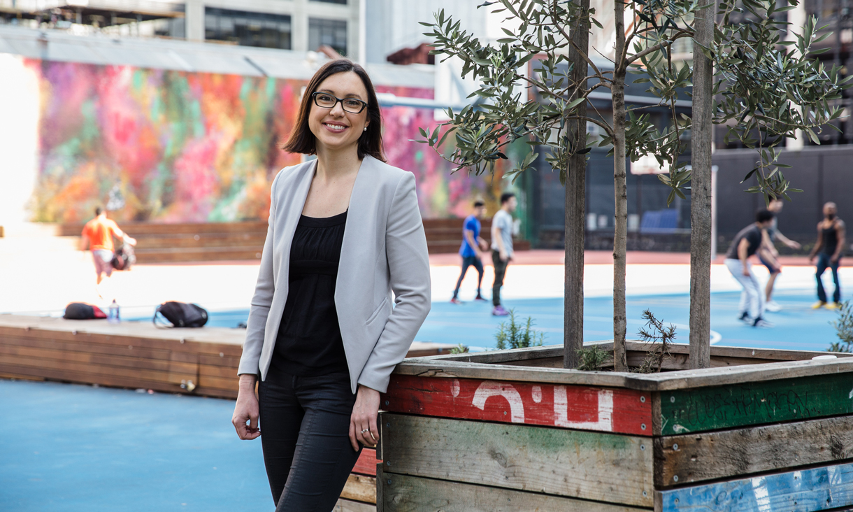 Emma Spano, RMIT Master of Urban Planning and Enviroment graduate,leaning against a planter box outside the RMIT basketball courts
