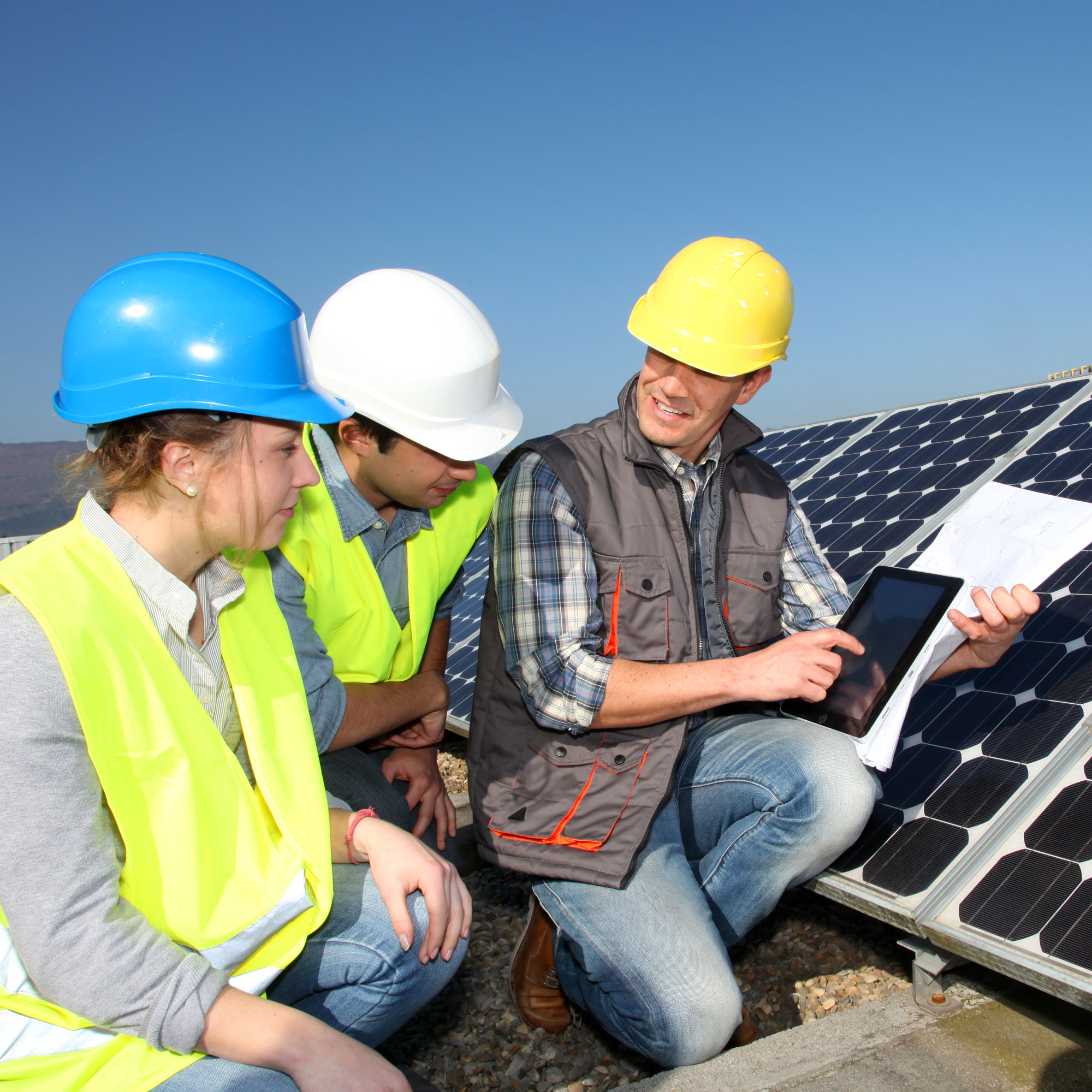 Tradespeople on a roof next to solar panels
