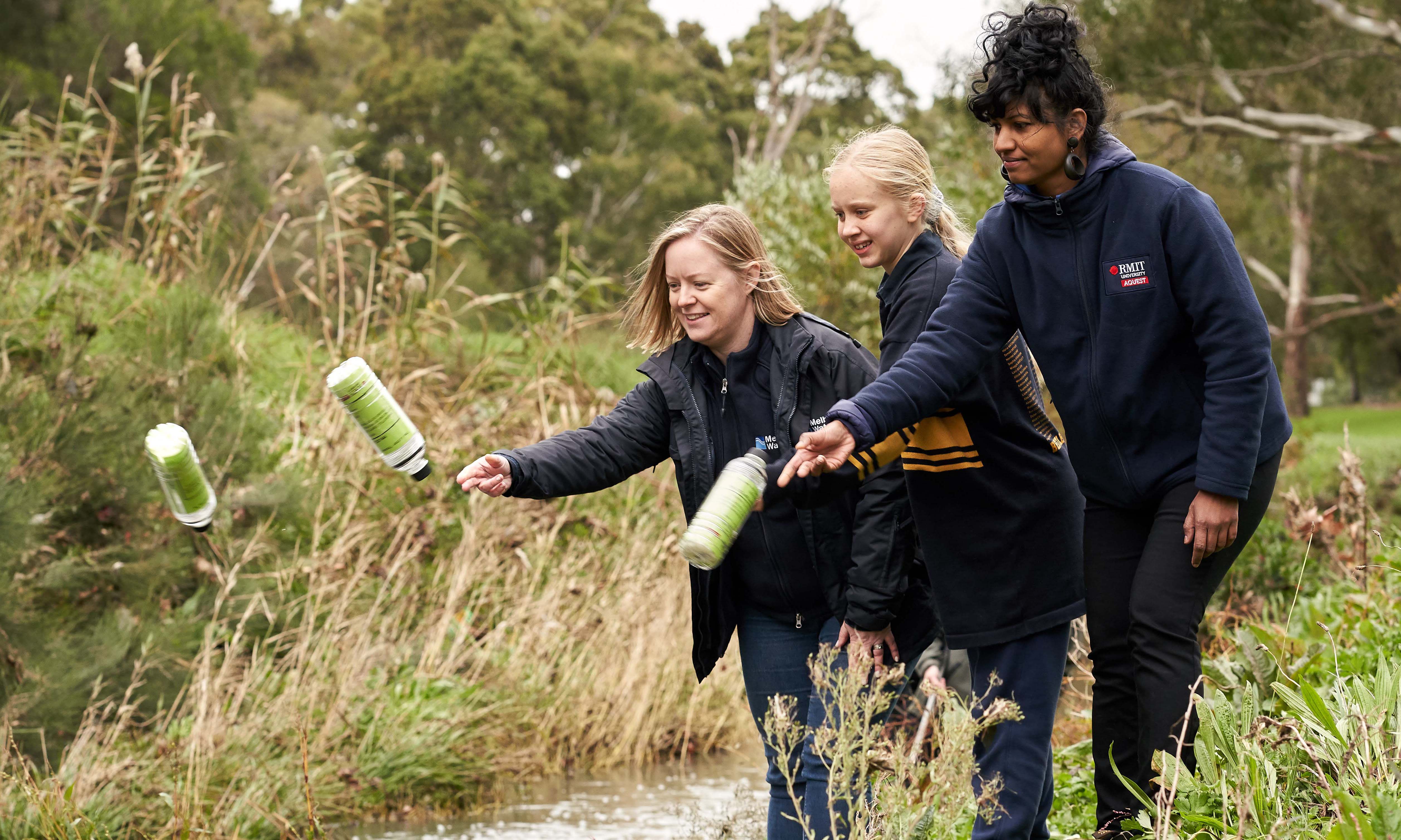 Melbourne Water’s Litter and Waterwatch Coordinator Naomi Dart, citizen scientist and Bentleigh West Primary School student Sophie Littlefair and RMIT’s Dr Kavitha Chinathamby launching GPS-tracked bottles into Dandenong Creek.