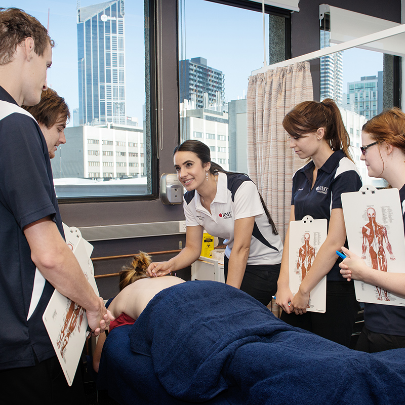 A group of students and teacher around a person receiving acupuncture 